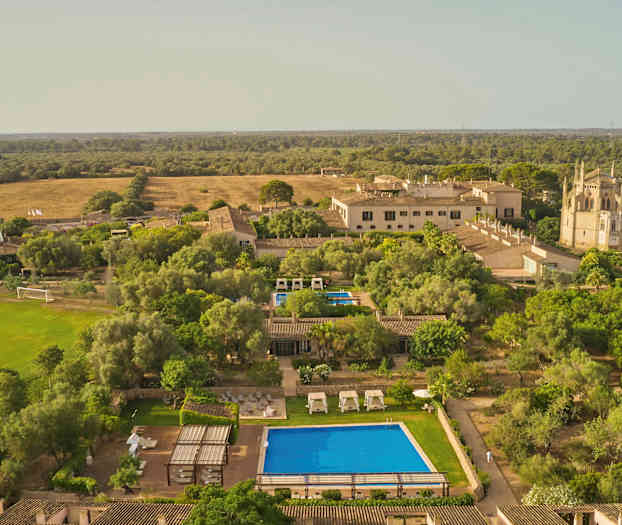 Luftfoto af en landlig ferieanlæg med pool og haver. (AI-genereret tekst)