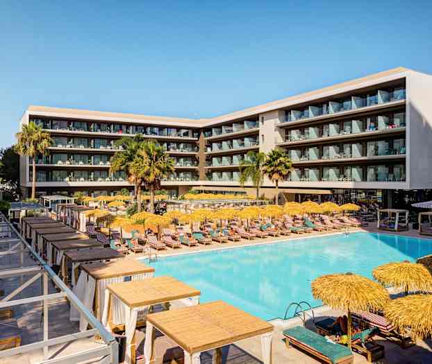 Et moderne hotel med en stor pool, liggestole og parasoller, omgivet af altaner. (AI-genereret tekst)