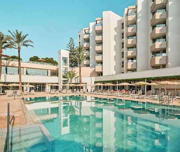 Et hotel med altaner omgiver en pool med liggestole og parasoller. (AI-genereret tekst)