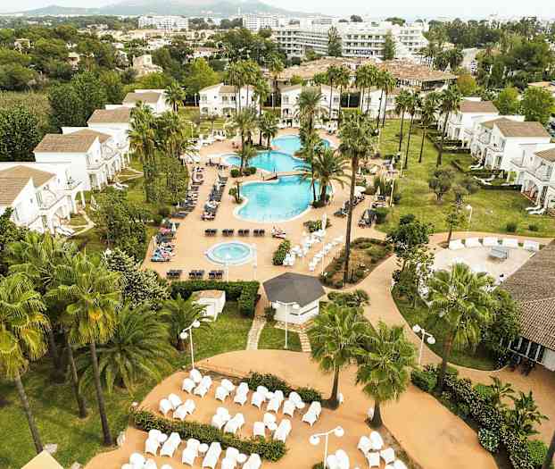 Et feriehotel med poolområde, grønne områder og bygninger i baggrunden. (AI-genereret tekst)