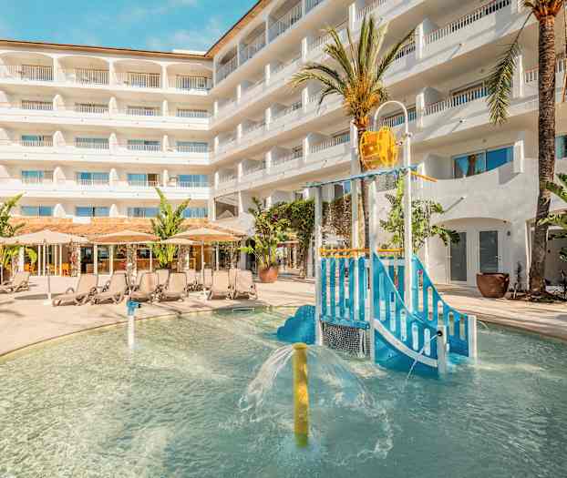 Udendørs poolområde med legeplads for børn og liggestole foran hotelbygning. (AI-genereret tekst)