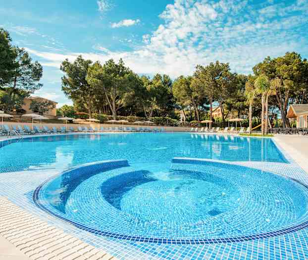 Udendørs swimmingpool omgivet af liggestole og træer. (AI-genereret tekst)