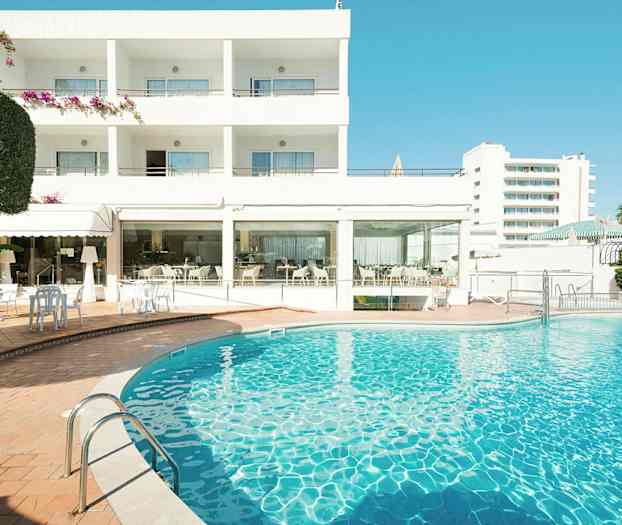 Hotelbygning med en udendørs swimmingpool i forgrunden. (AI-genereret tekst)