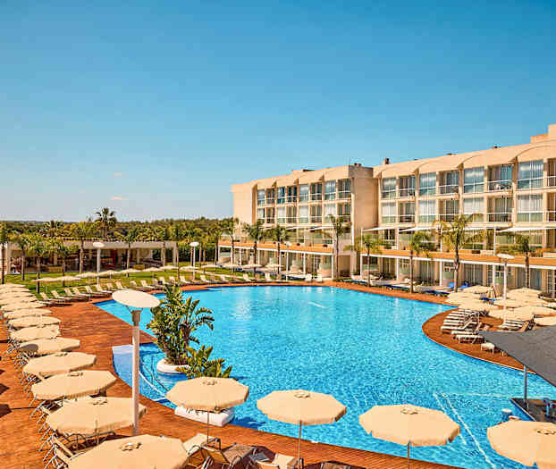 Billede af et hotel med en stor pool, solsenge og parasoller. (AI-genereret tekst)