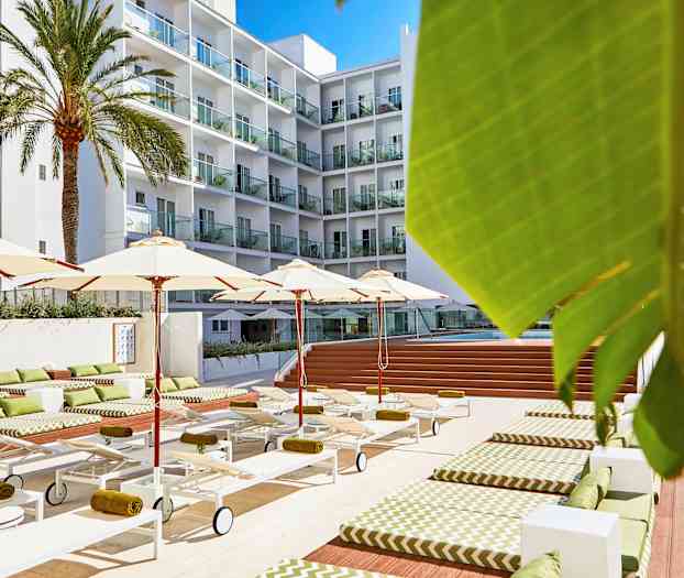 Hotelpoolområde med liggestole, parasoller og en fleretagers bygning i baggrunden. (AI-genereret tekst)