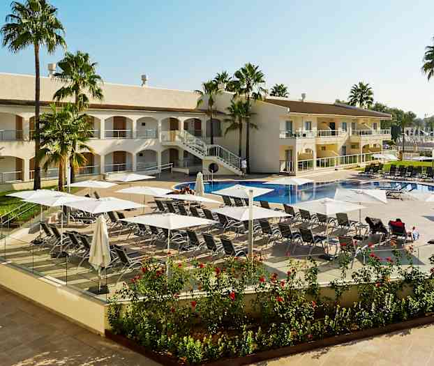 Billede af en hotelpool med liggestole og parasoller, omgivet af palmer og hotellet. (AI-genereret tekst)