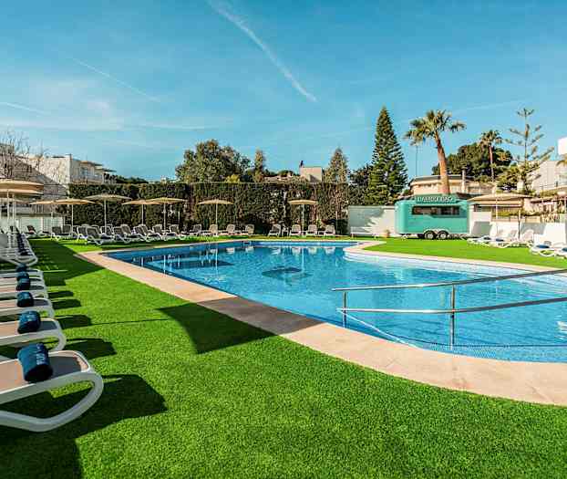 Udendørs swimmingpool med liggestole og grønne omgivelser. (AI-genereret tekst)