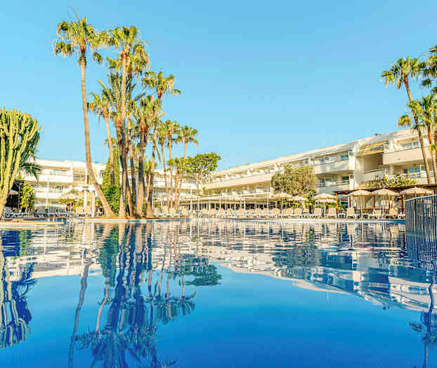 Billede af et hotel med palmer ved en pool. (AI-genereret tekst)