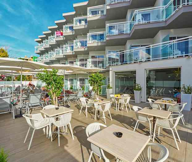 Udendørsområde med borde og stole samt liggestole ved et hotel med altaner. (AI-genereret tekst)