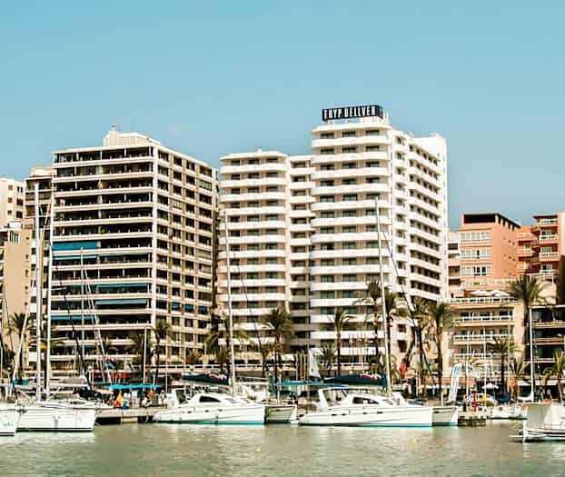 Et billede af en havn med sejlbåde og høje bygninger i baggrunden. (AI-genereret tekst)