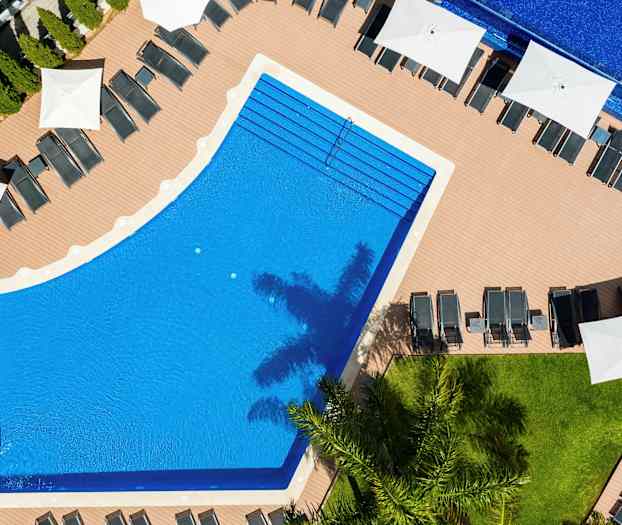 Luftfoto af en pool omgivet af liggestole og parasoller. (AI-genereret tekst)