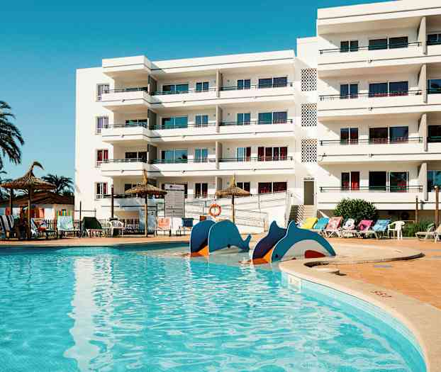 En swimmingpool foran en hvid bygning med altaner. (AI-genereret tekst)