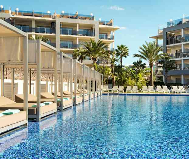 Udendørsområde med pool, liggestole og hotelbygninger. (AI-genereret tekst)