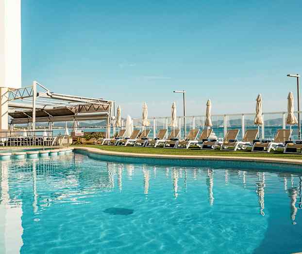 Udendørs pool med liggestole og parasoller ved siden af. (AI-genereret tekst)