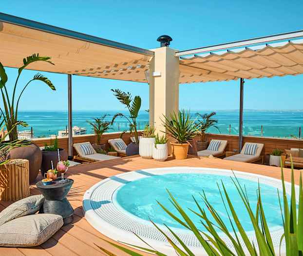 Terrasse med jacuzzi, liggestole og havudsigt. (AI-genereret tekst)
