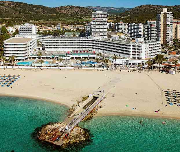 Billede af en sandstrand med liggestole og parasoller, en bro der fører ud i havet, og hotelbygninger i baggrunden. (AI-genereret tekst)