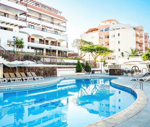 Udendørs pool med liggestole og parasoller ved et hotel. (AI-genereret tekst)