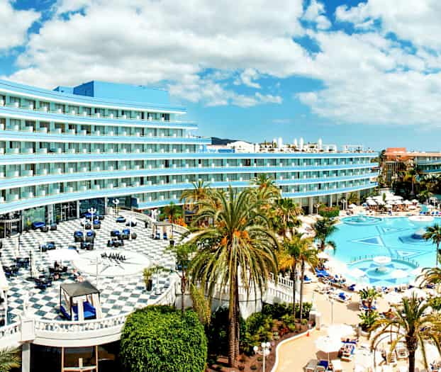 Billede af hotel med pool og palmer. (AI-genereret tekst)