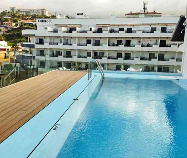 Billede af en swimmingpool med udsigt over en beboelsesejendom i baggrunden. (AI-genereret tekst)