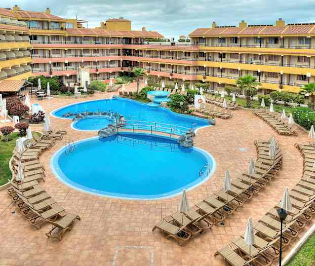 En hotelpool omgivet af liggestole. (AI-genereret tekst)