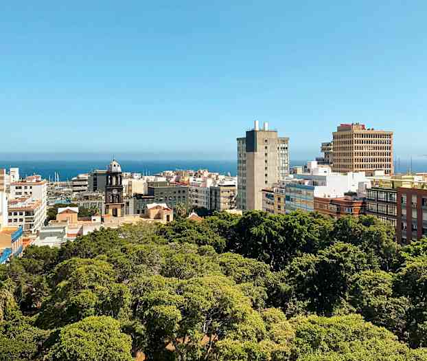 Byudsigt med bygninger og grønt område, havet ses i baggrunden. (AI-genereret tekst)