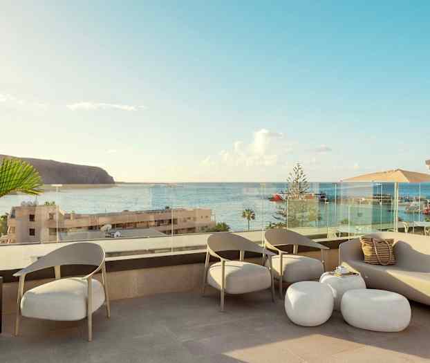 En terrasse med siddepladser og udsigt over havet og en havn. (AI-genereret tekst)