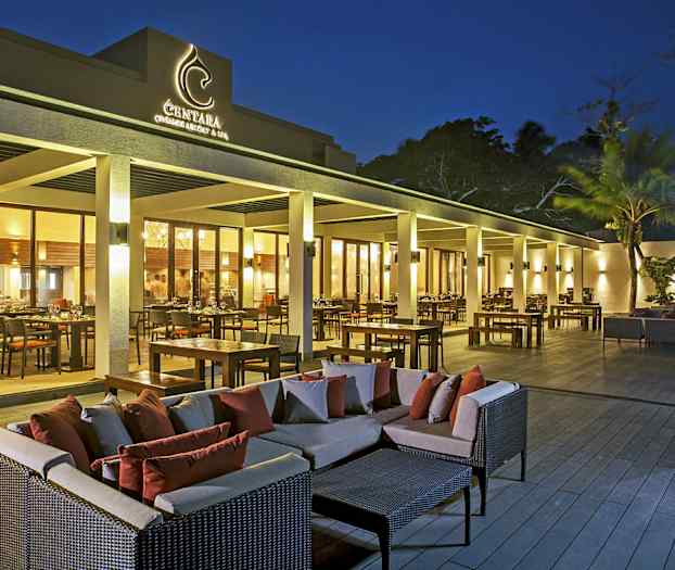 En udendørs terrasse ved en restaurant med borde, stole og sofagrupper i skumringslys. (AI-genereret tekst)