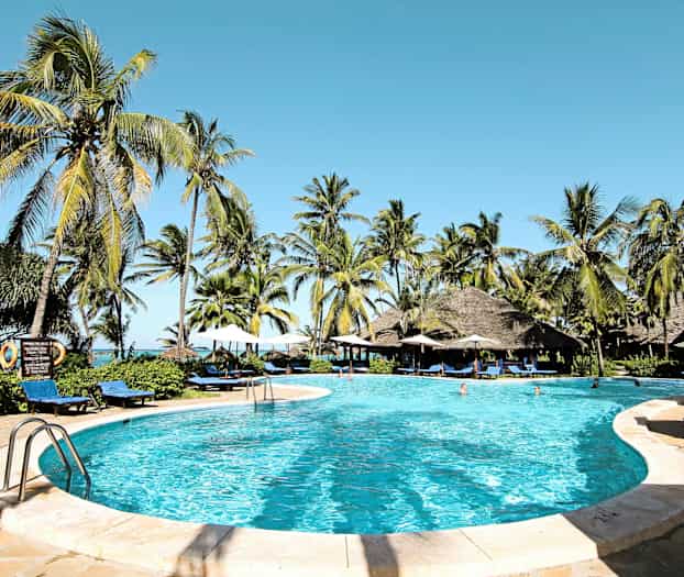 Billede af en pool omgivet af liggestole, parasoller og palmer med en klar blå himmel. (AI-genereret tekst)