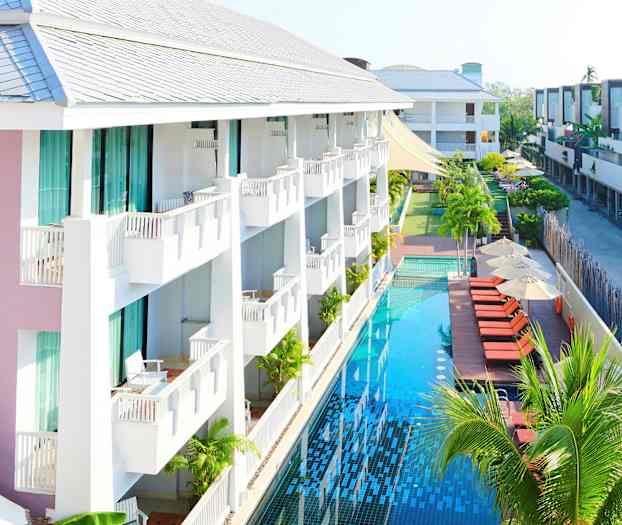 Et hotel med altaner og en lang pool ved siden af solsenge og parasoller. (AI-genereret tekst)