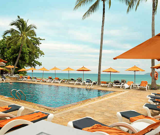 Udendørs pool omgivet af liggestole og parasoller, med udsigt over havet. (AI-genereret tekst)