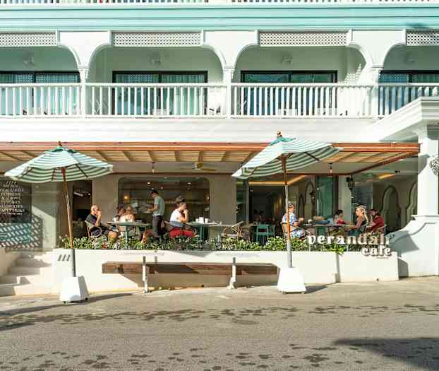 Udendørs billede af en café med parasoller og siddepladser. (AI-genereret tekst)