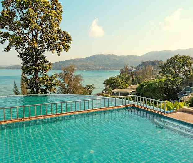 Udsigt over swimmingpool med hav og bjerge i baggrunden. (AI-genereret tekst)