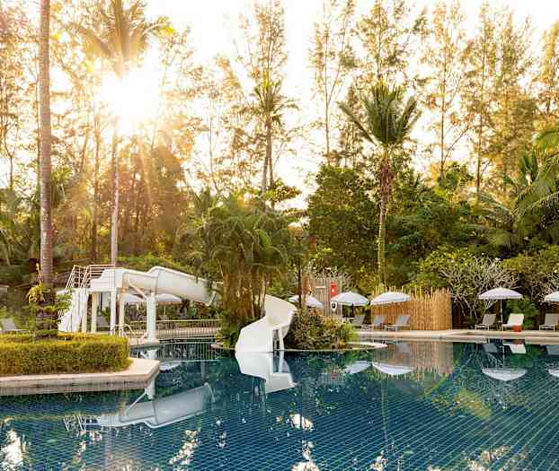 Poolområde med vandrutsjebane, omgivet af solvogne og bevoksning. (AI-genereret tekst)