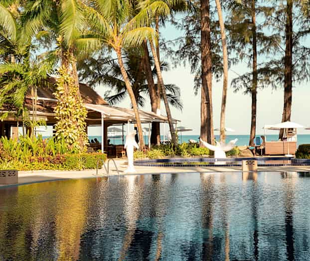 Pool og tropiske træer med udsigt til havet. (AI-genereret tekst)