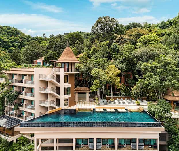 Et feriested omgivet af grønne områder med en infinity-pool i forgrunden. (AI-genereret tekst)