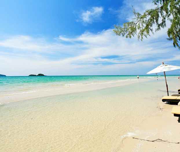 En sandstrand med klart vand, liggestole og parasoller i kanten. (AI-genereret tekst)