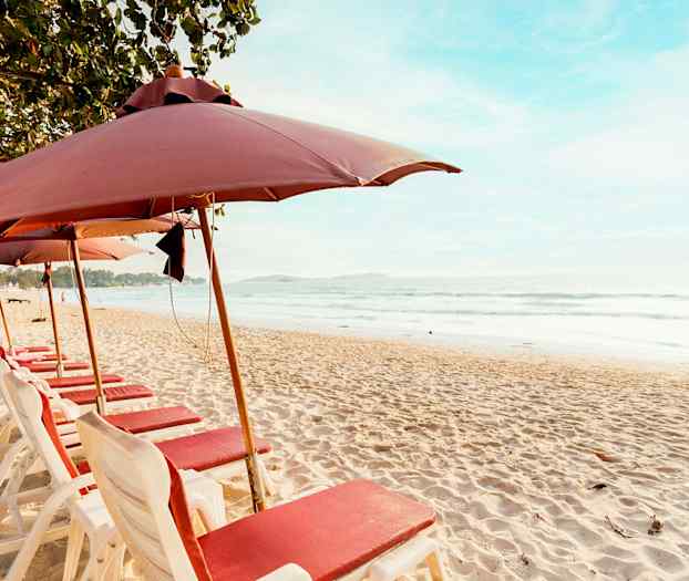 Strand med liggestole og parasoller på række ved havet. (AI-genereret tekst)