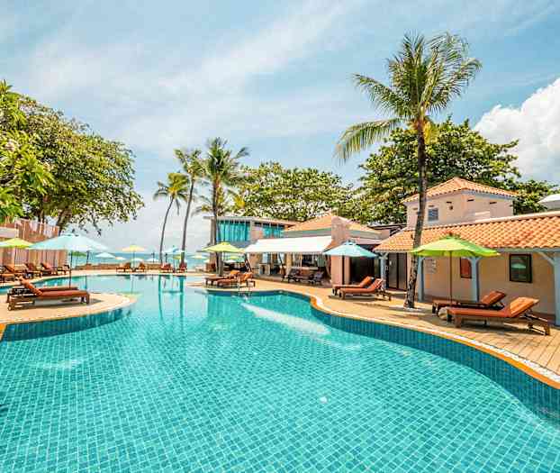 Poolområde med parasoller og liggestole ved et ferieanlæg. (AI-genereret tekst)