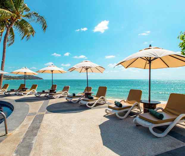 Strand med liggestole og parasoller ved en pool tæt på havet. (AI-genereret tekst)