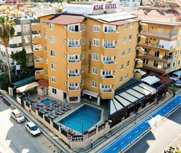 Et hotel ved en vej med en udendørs pool, liggestole og en lille siddegruppe. (AI-genereret tekst)