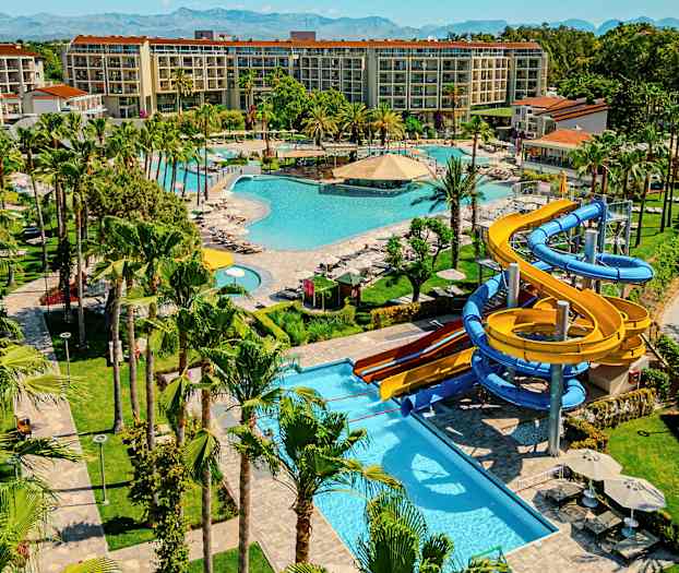 En resort med flere pools, grønne områder og vandrutsjebaner. (AI-genereret tekst)