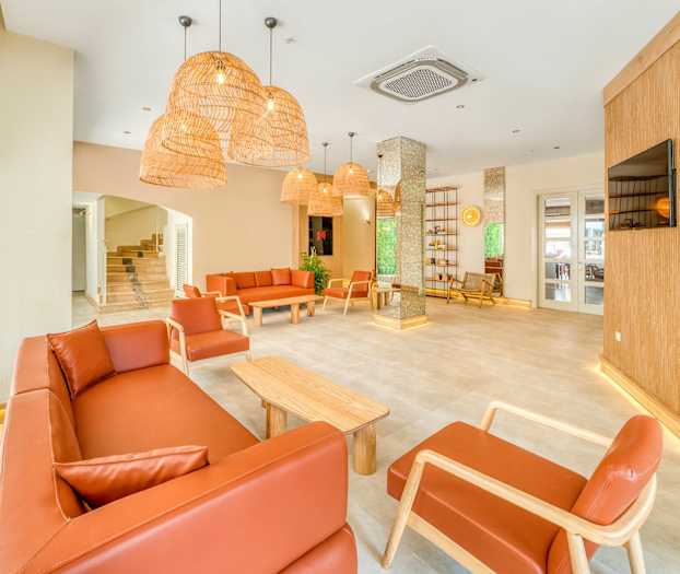 En lys lounge med brune sofaer og lænestole, træborde og hængende lamper af rattan. (AI-genereret tekst)