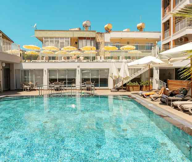 En udendørs pool omgivet af liggestole og parasoller på et hotel. (AI-genereret tekst)
