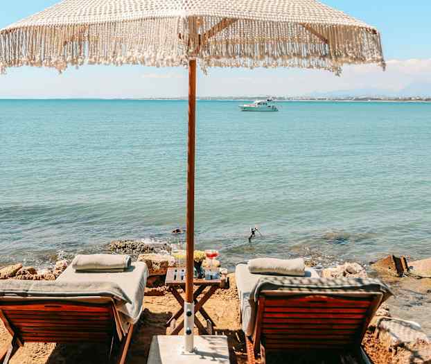 To liggestole med parasol ved havet. (AI-genereret tekst)