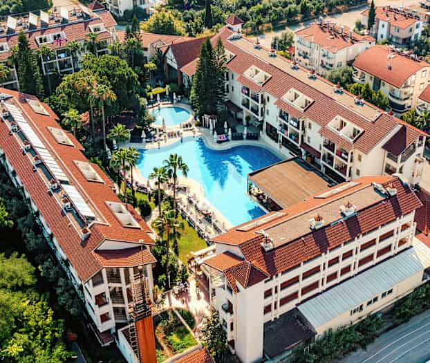 Luftfoto af hotelkompleks med pool og omkringliggende bygninger. (AI-genereret tekst)