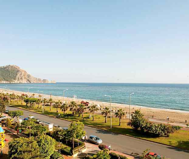 En kyststrækning med strand, hav og en vej med grønne områder. (AI-genereret tekst)