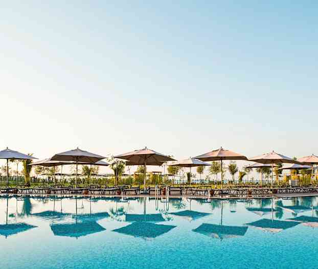 En swimmingpool med liggestole og parasoller ved kanten. (AI-genereret tekst)