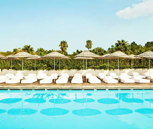 Pool med liggestole og parasoller i baggrunden. (AI-genereret tekst)
