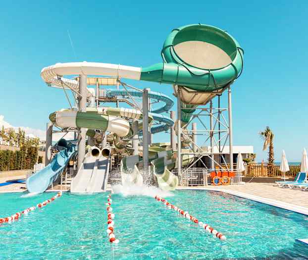 Billedet viser en vandpark med flere store vandrutsjebaner og en pool i forgrunden. (AI-genereret tekst)