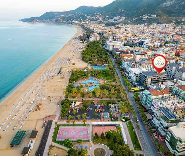 Luftfoto af en strand med liggestole ved siden af bygninger og træer. (AI-genereret tekst)